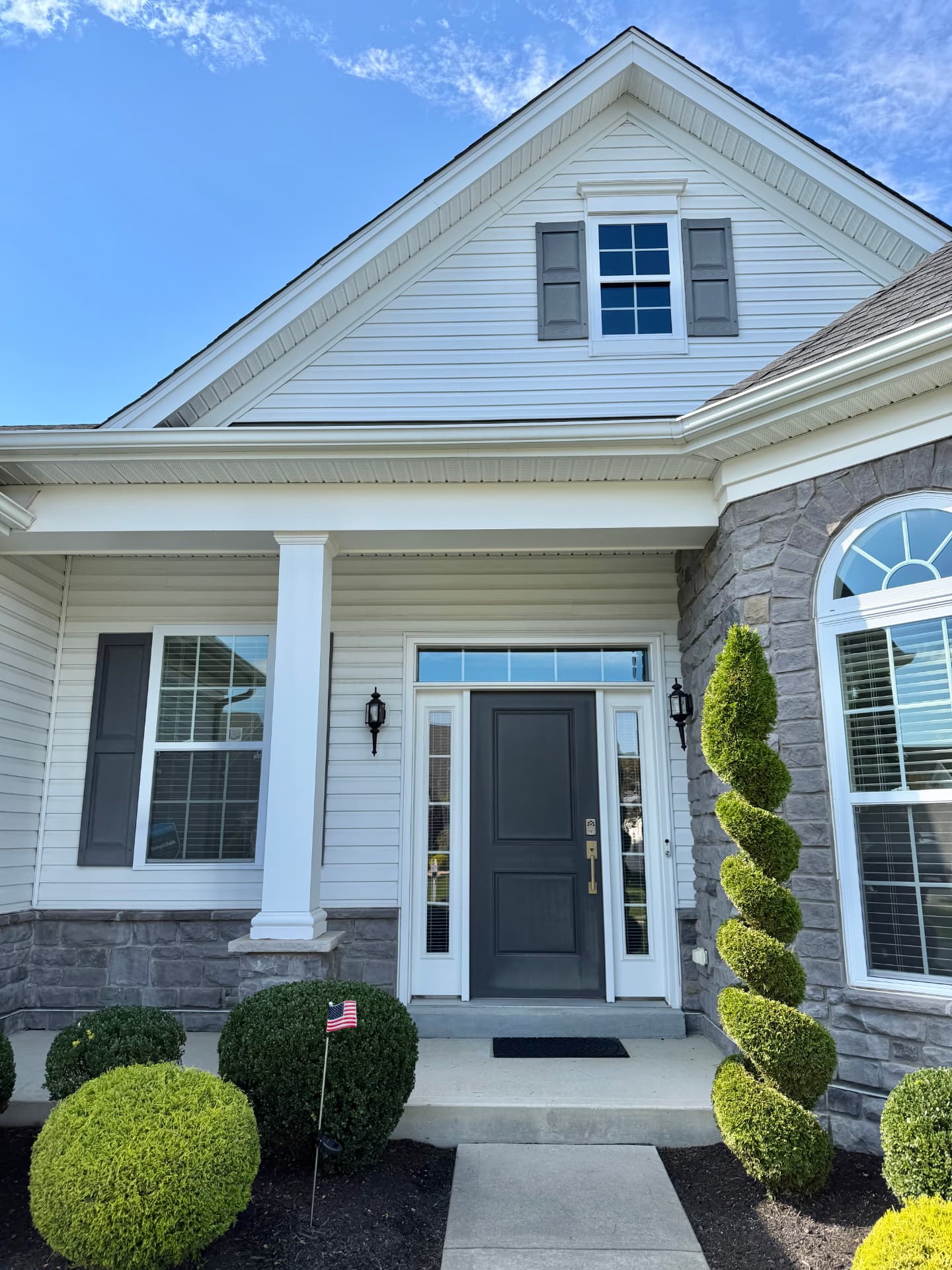 Home entry with a charcoal front door and shutters beside freshly painted white trim